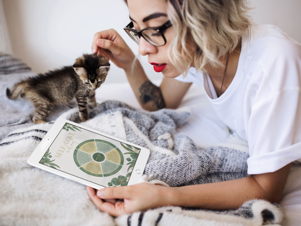Photo of a woman with a kitten looking at the Self Love Wheel Image on an Ipad